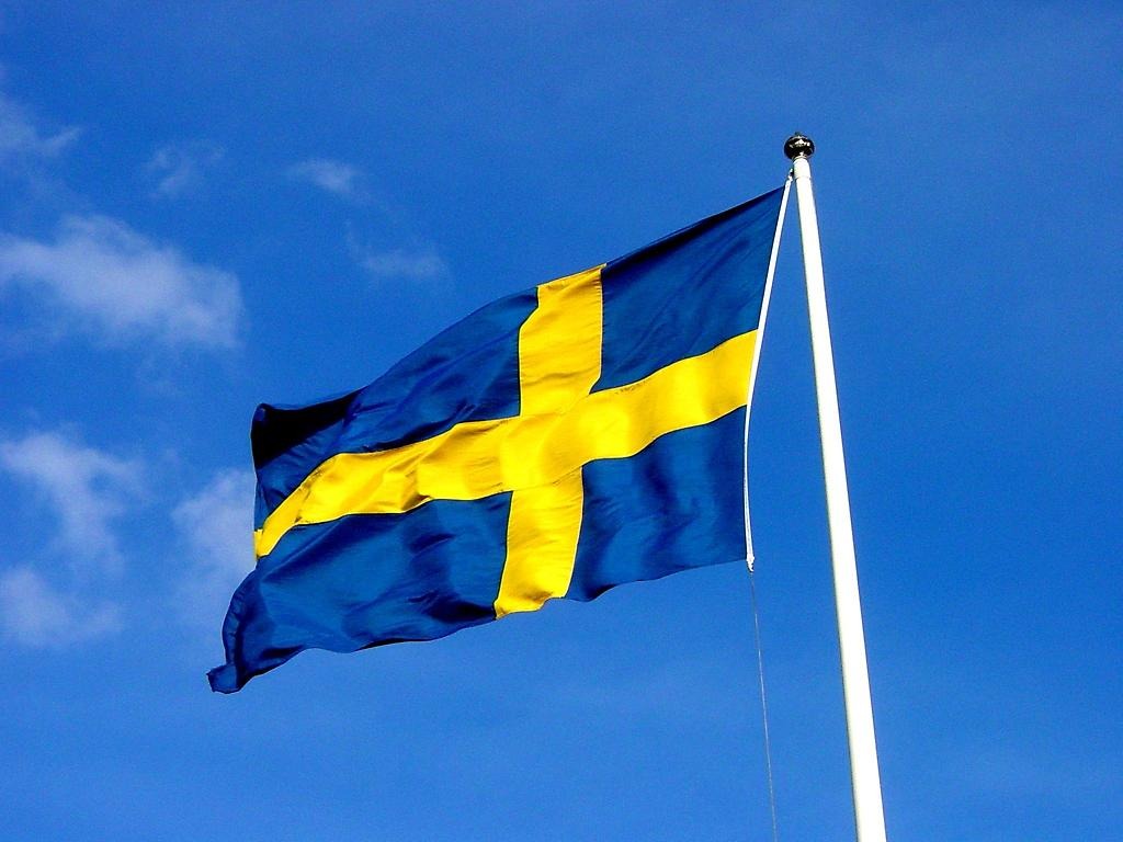 Svenska flaggan som är hissad och blåser i vinden. 