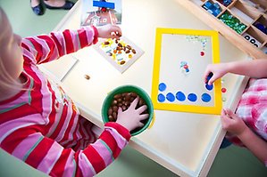 Barn leker med färgglada kulor och brickor på ett dagis.