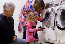 En familj tar ut tvätt ur en tvättmaskin.