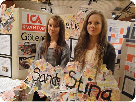 Två unga tjejer visar upp ihopklistrat tidningspapper med namnen Sandra och Stina på.