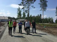 Representanter för husföretag går på en grusväg i ett villaområde i Källby.