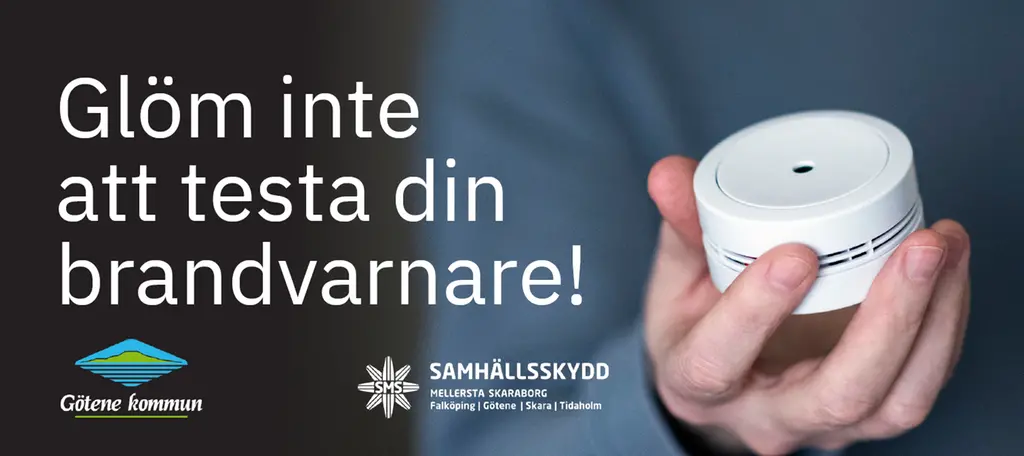 En hand som håller i en brandvarnare med texten "Glöm inte att testa din brandvarnare!" tillsammans med Götene kommuns logotyp och Samhällsskydd Mellersta Skaraborgs logotyp.