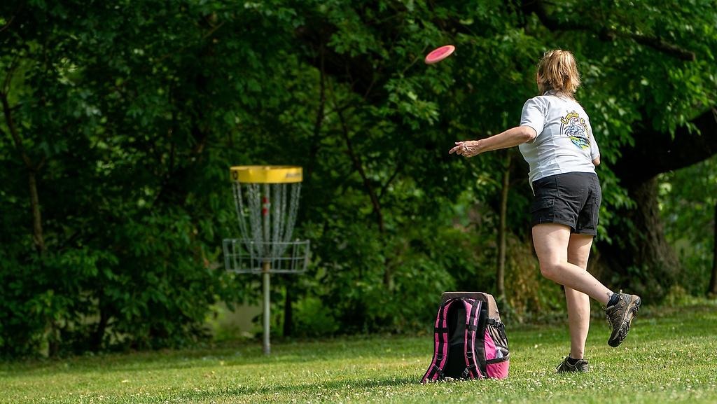Flicka som kastar en frisbee in i ett mål.