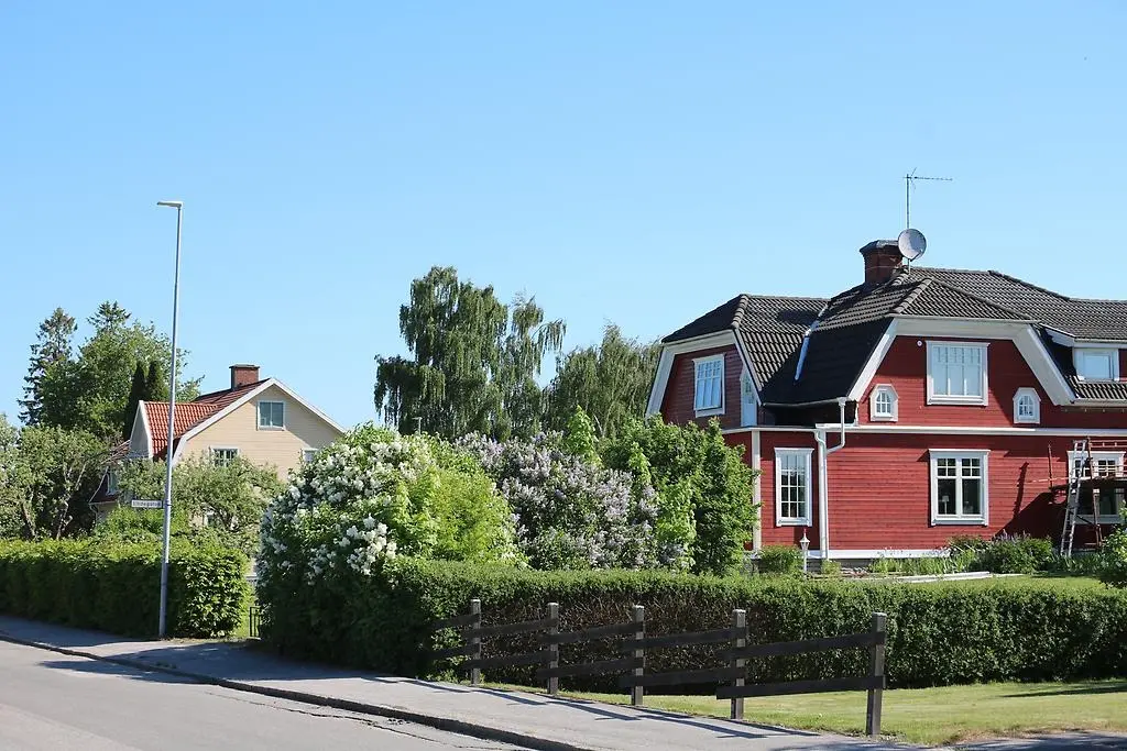 En bild som visar två villor med trädgårdar med häckar och fruktträd.