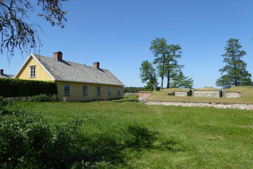 En bild som visar en ruin, gräs och en gulmålad byggnad.