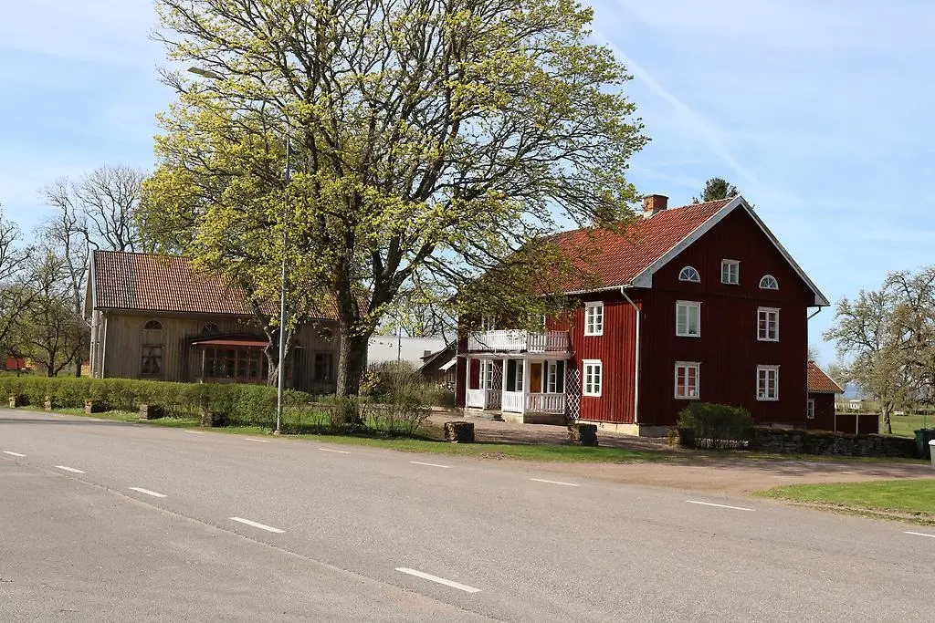 En bild som visar två äldre byggnader, en röd och en omålad.