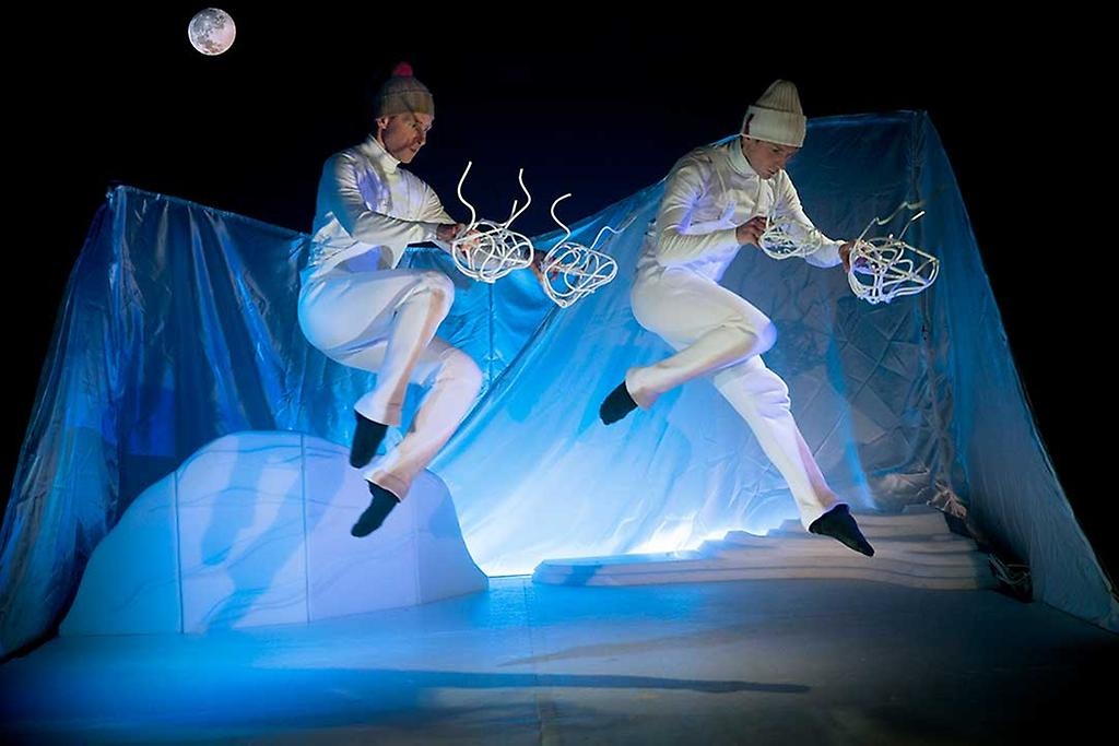 Två dansare i vita kläder i en fiktiv fjällmiljö.
