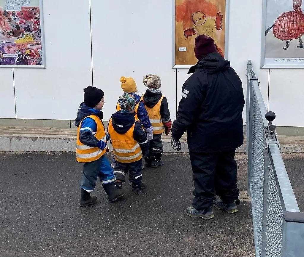 Barn i reflexvästar som tittar på ett konstverk.