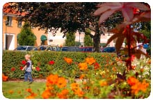 Park med buskar och blommor. Ett barn går på gången en bit bort.