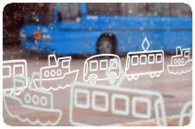 En blå buss sedd genom ett busshållsplats plexiglas.