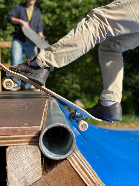 Två fötter på en skateboard som är på väg ner för en blå ramp.