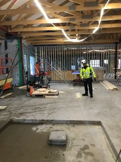 Man i bygghjälm och reflexjacka visar bygget.