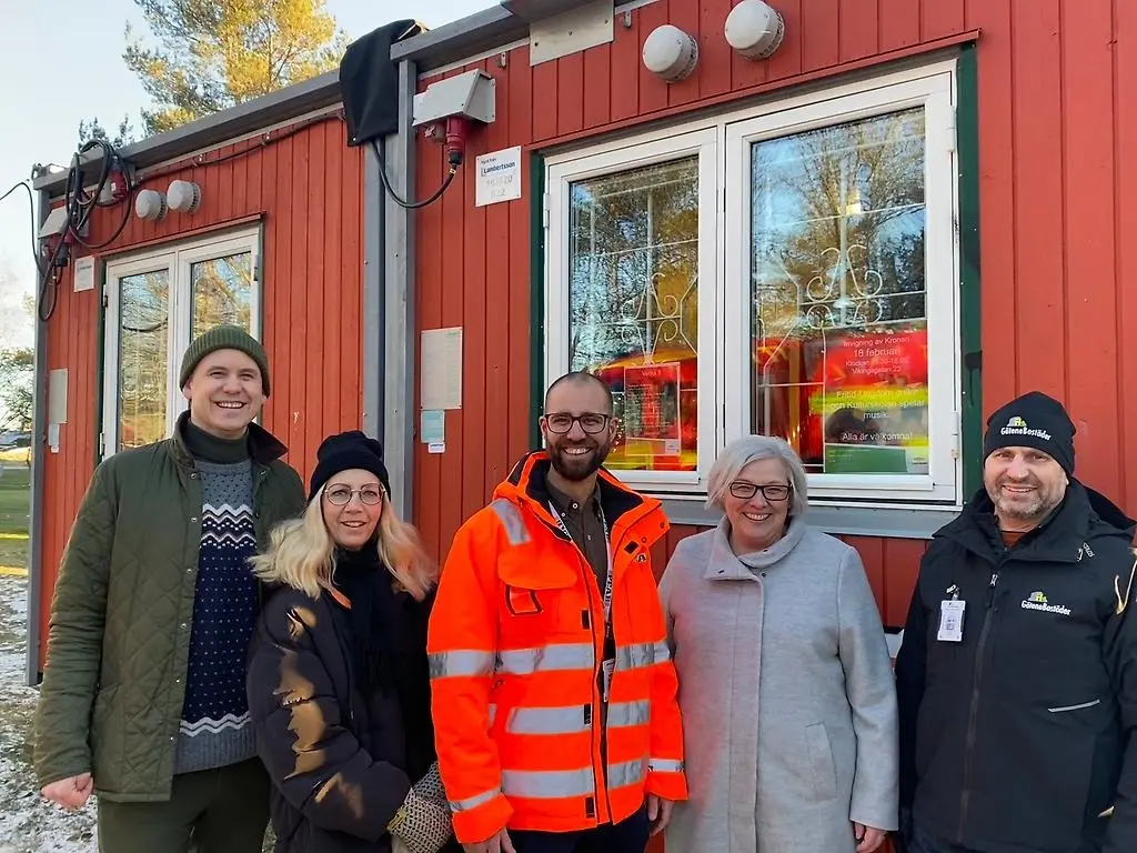 Fyra personer, två män och två kvinnor, står framför en röd bod iklädda vinterjackor och ler.