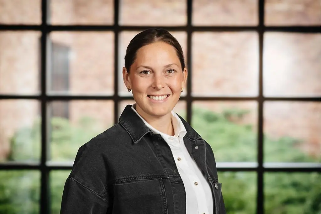 Leende kvinna. Hon har en vit skjorta på sig med en svart jacka över. 