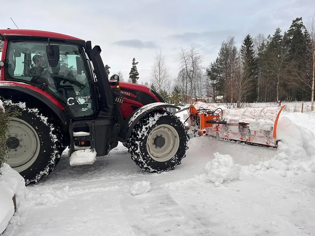 Traktor med plogblad som plogar snö på villagata.