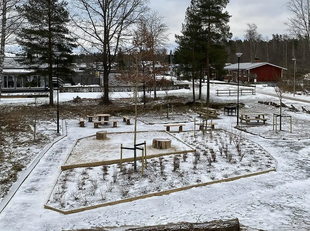 Sittgrupper täckta av snö i anslutning till lekplatsen.