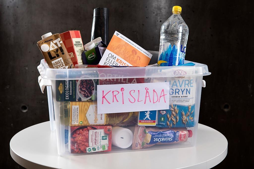 En plastlåda som det står "Krislåda" på. I lådan ligger olika livsmedel, redskap och informationsbroschyrer. 