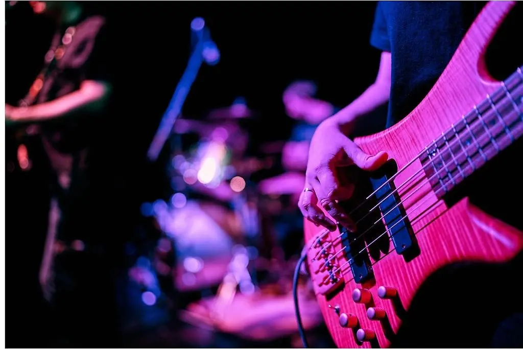 en närbild på en man som spelar på en elbas på en scen.