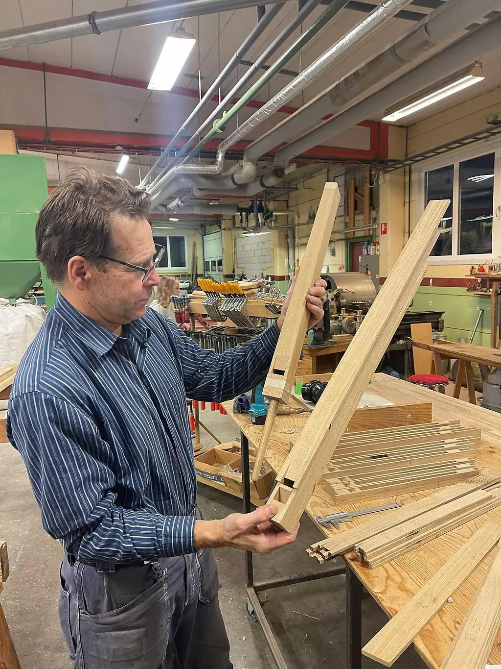 Man håller i två stycken träpipor till en orgel i en verkstad.