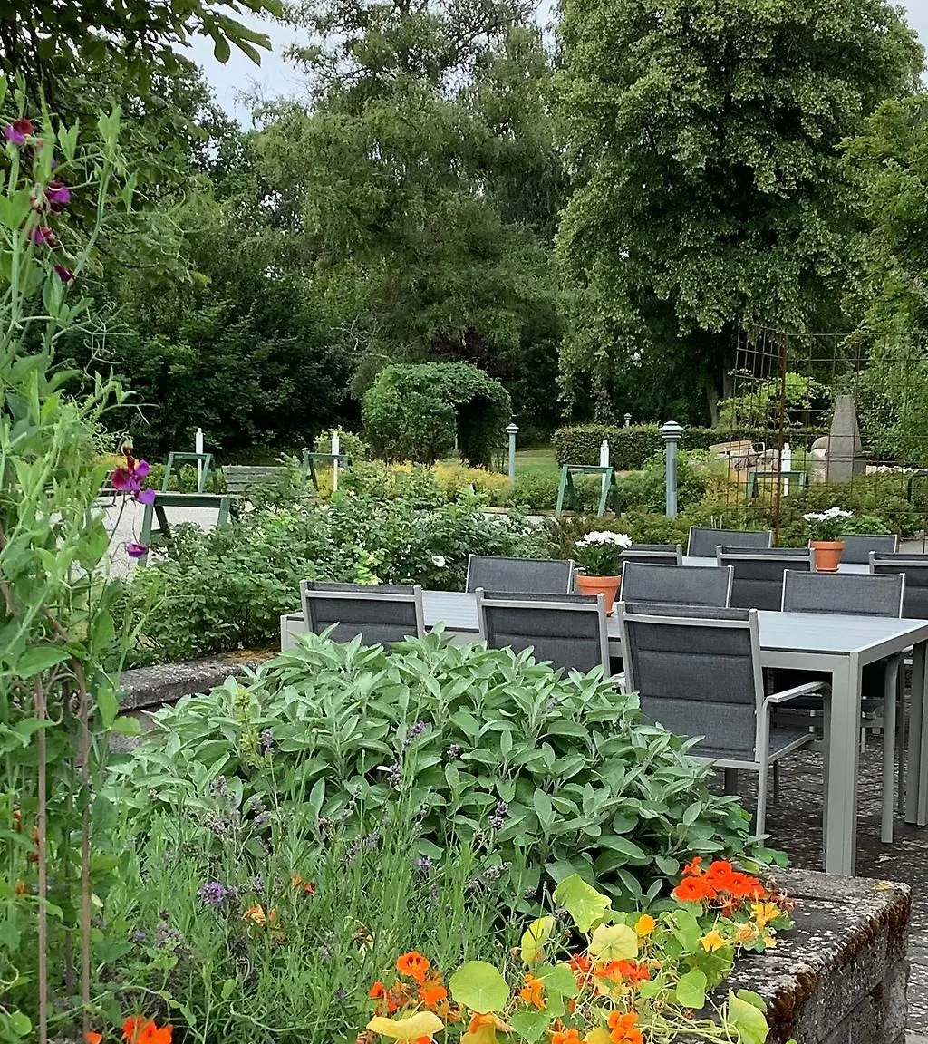 Bland blommande buskar står Café Helenas uteservering. 