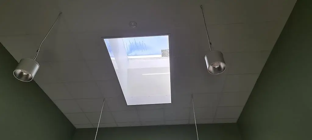 Ett stort takfönster som lyser upp ett rum med milt grönmålade väggar.