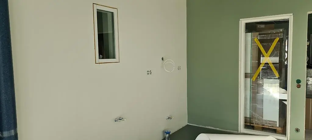 Ett rum med milt grönmålade väggar, ett litet inomhusfönster samt ett större.