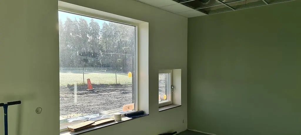 Ett stort och ett litet fönster i ett rum med milt grönmålade väggar.