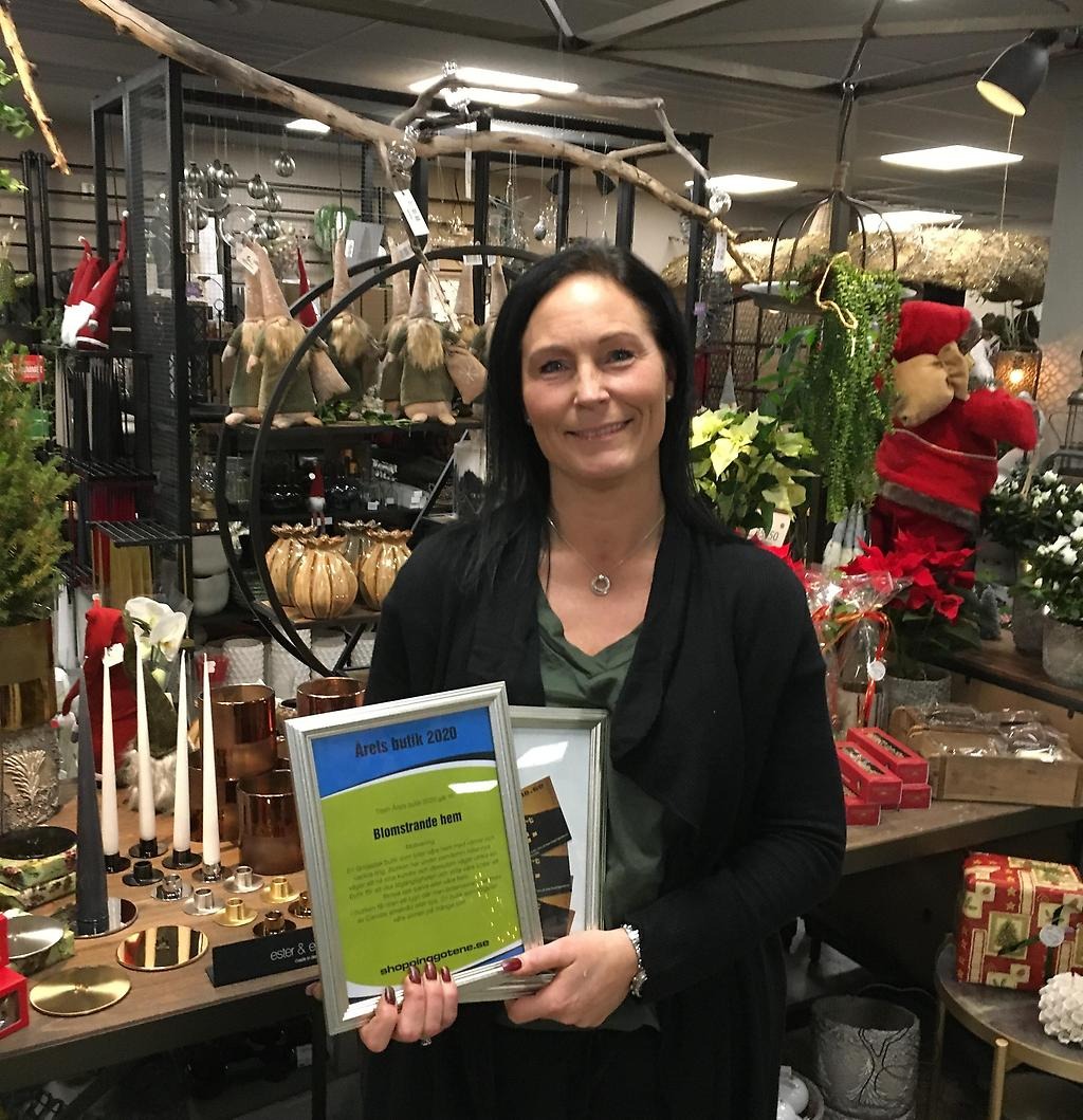 Förra årets vinnare håller upp diplom med text "årets butik 2020, Blomstrande hem". 