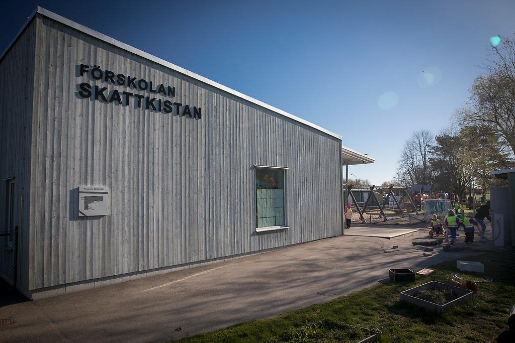 En grå träbyggnad med skylten förskolan Skattkistan.