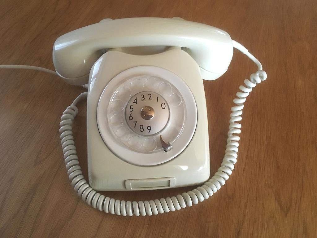Klassisk telefon med nummerskiva i färgen vit. 