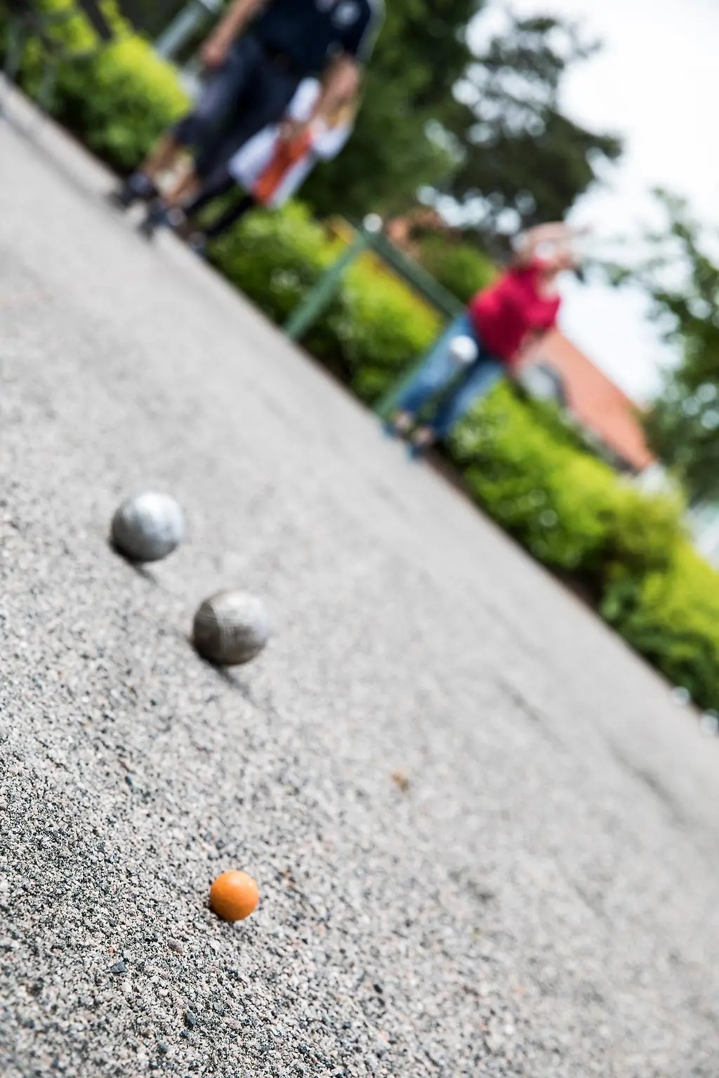 Närbild på boulekulor, i en ofokuserad bakgrund ser man spelarna.
