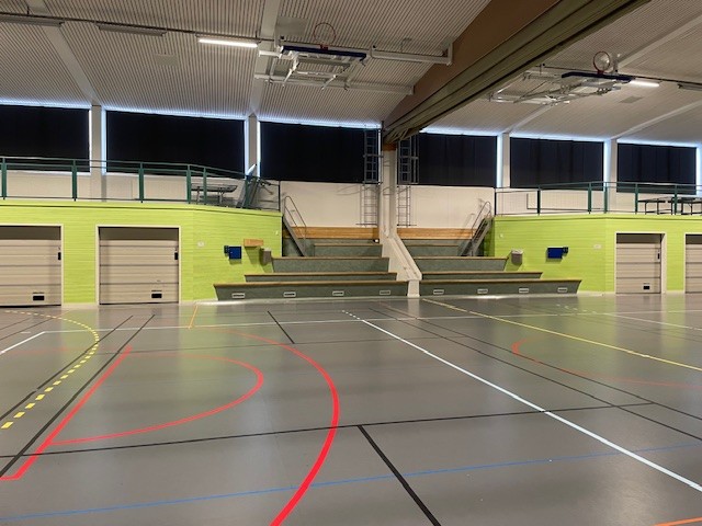 Grönfärgade väggar, sittplatser emellan. Grått golv med färgade streck över.