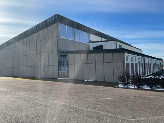 En stor grå byggnad med vita spröjs runt dörrar och fönster