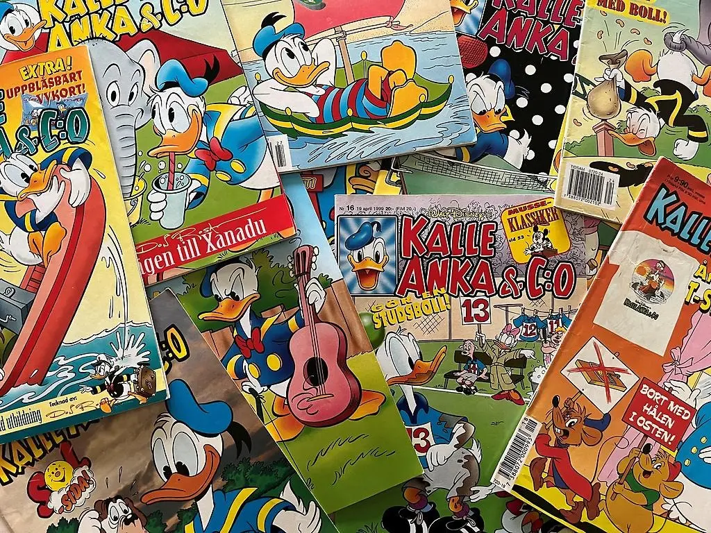 Bilden visar ett stort gäng Kalle Ankaserietidningar som ligger utspridda över ett bord.