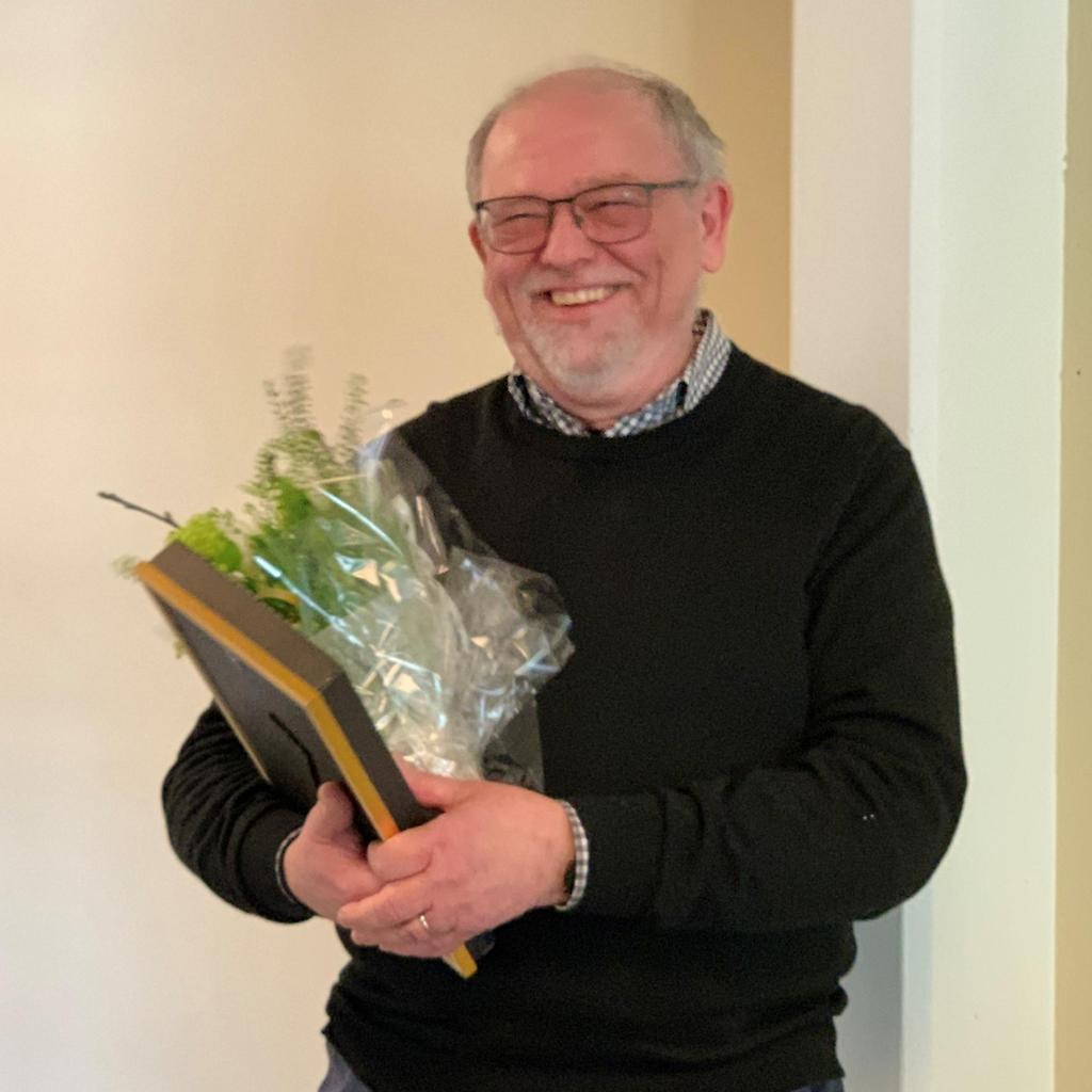 En glad Sten Ollars med blommor och diplom i handen.