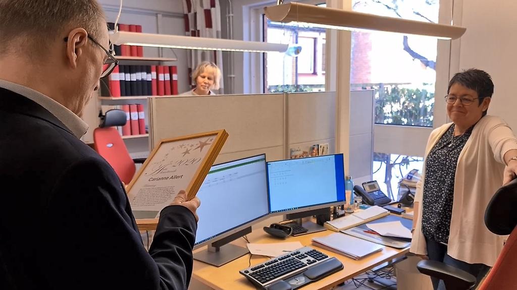 Uppläsning av motiveringen från diplomet för årets bemötande 2020 framför två glada mottagare.