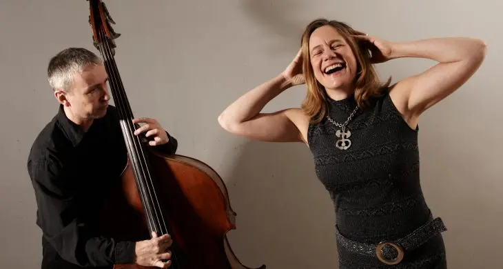 En man spelar på en kontrabas, bredvid står en leende kvinna.