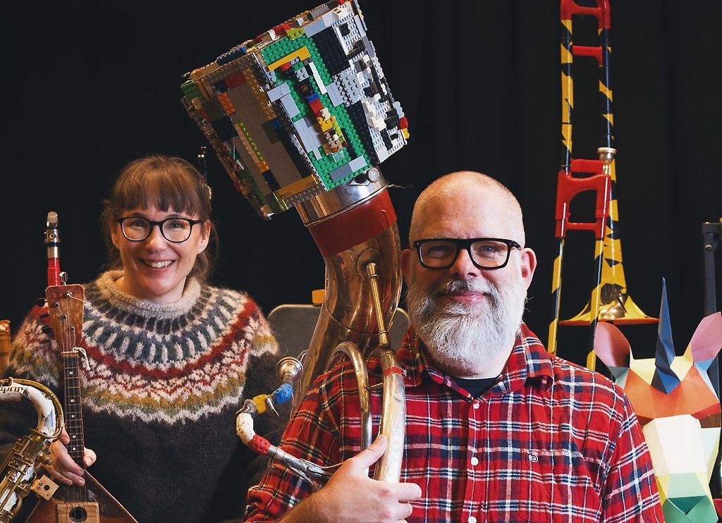 En man och en kvinna står bredvid varandra med specialbyggda instrument av skrot.