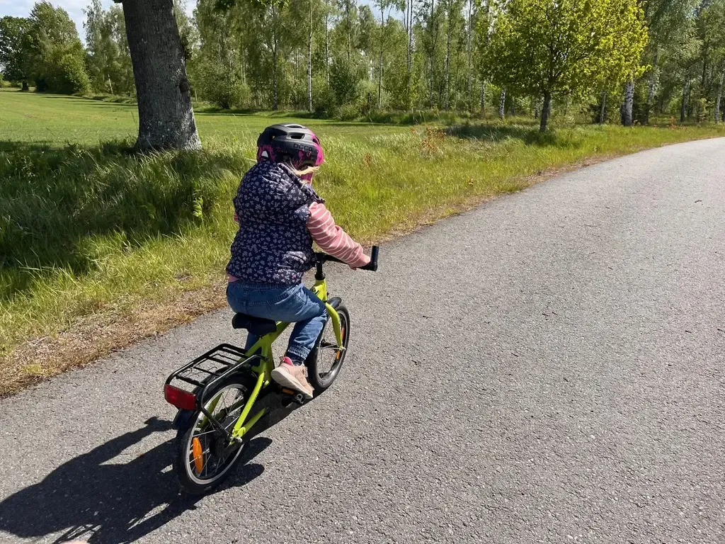Barn som cyklar på en asfaltsväg.