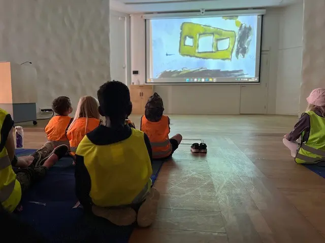 Förskolebarn som sitter och tittar på en film.
