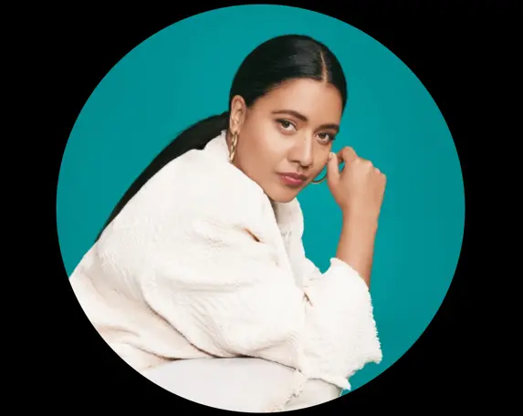 Kvinna med mörkt hår sitter framåtlutad i profil.