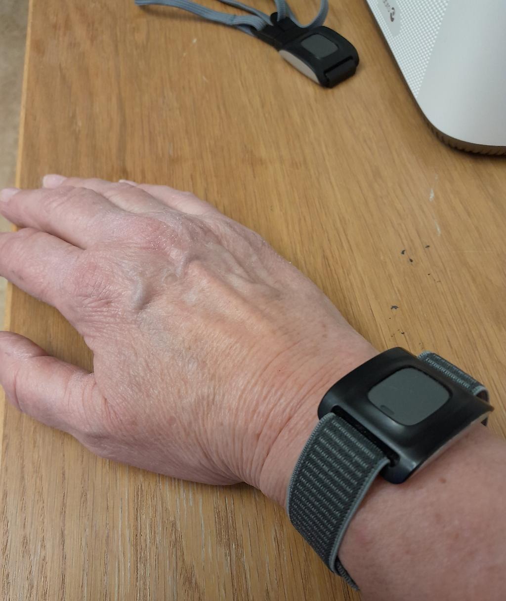 Bilden visar en underarm med ett trygghetslarm runt handleden