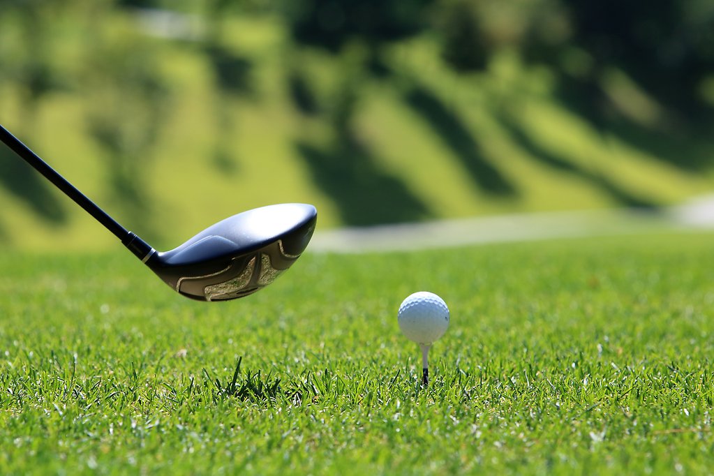 Bakgrunden är grönt gräs med en vit boll som ligger på en golfpeg.