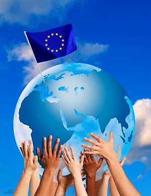 En jordglob med EU:s flagga på toppen hålls upp av flera händer mot himlen.