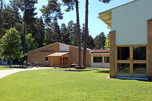 Ljungsbackenskolan. Två byggnader med gult tegel och vitt en solig sommardag.