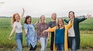 Sex kvinnor står på ett fält och håller ut armarna.