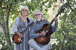 Man och kvinna håller i varsitt instrument utomhus. 