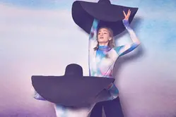 Två människor dansar med två jättestora hattar.