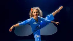 Kvinna som dansar i en blå dräkt i ett mörkt rum.