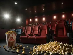 En biosalong med röda stolar, mörkt med enstaka strålkastare som lyser upp salongen. Framför första raden stolar ligger popcorn utspritt och bredvid står en stor rödvitrandig popcornbägare.